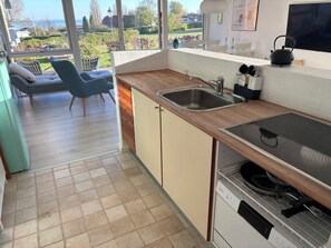 A modern kitchen with a large window, a sink, a stove, and a dining area with chairs. - Lovely secluded holiday home near beach (Sydals)