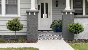 A house with a front porch, a door, and two small trees.