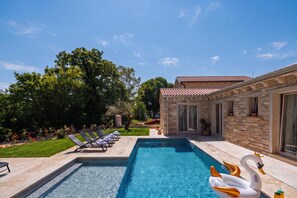 A swimming pool with lounge chairs and a swan floatation device. - Villa Stonica - Rustic Istrian Pool Retreat (Tinjan)