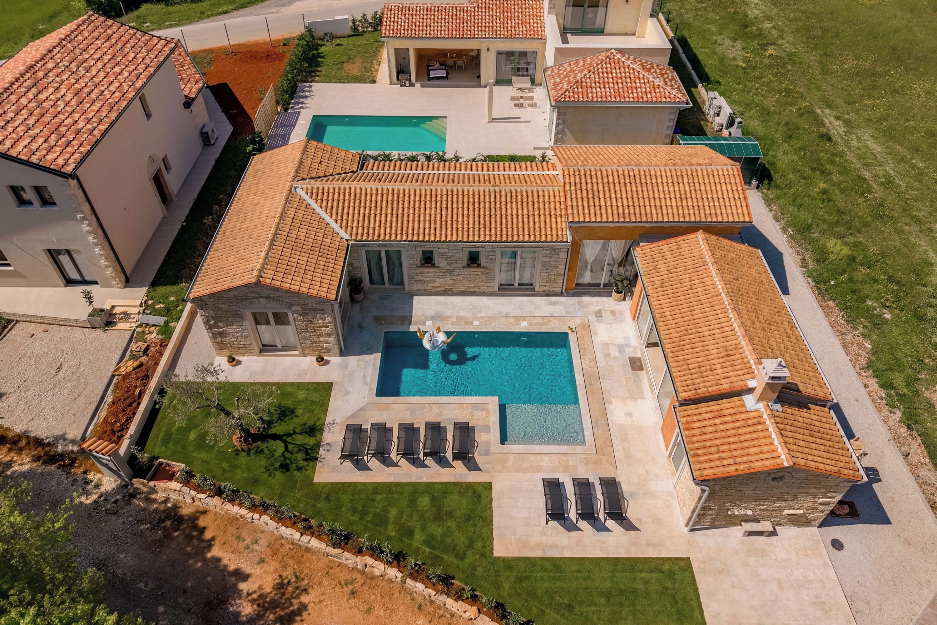 Um imóvel residencial com piscina, vários quartos e gramado bem cuidado.