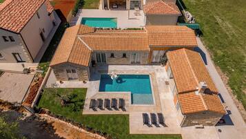 Um imóvel residencial com piscina, vários quartos e gramado bem cuidado.