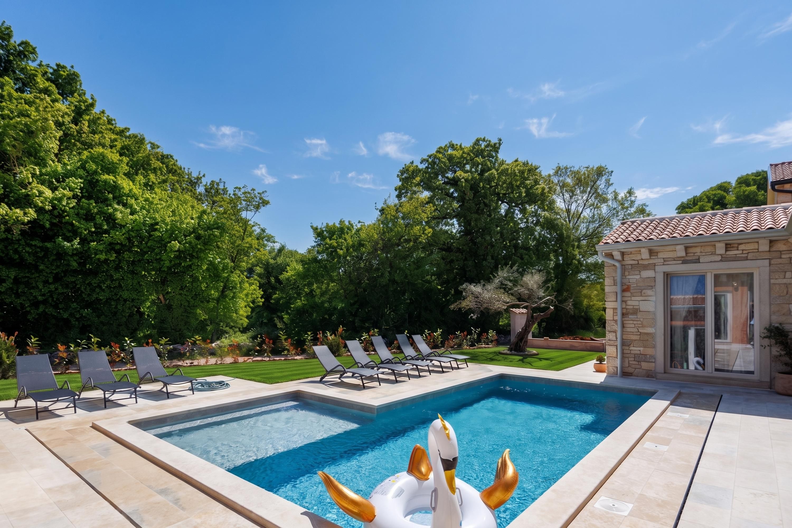 Una piscina con sillones de descanso y un flotador con forma de cisne.