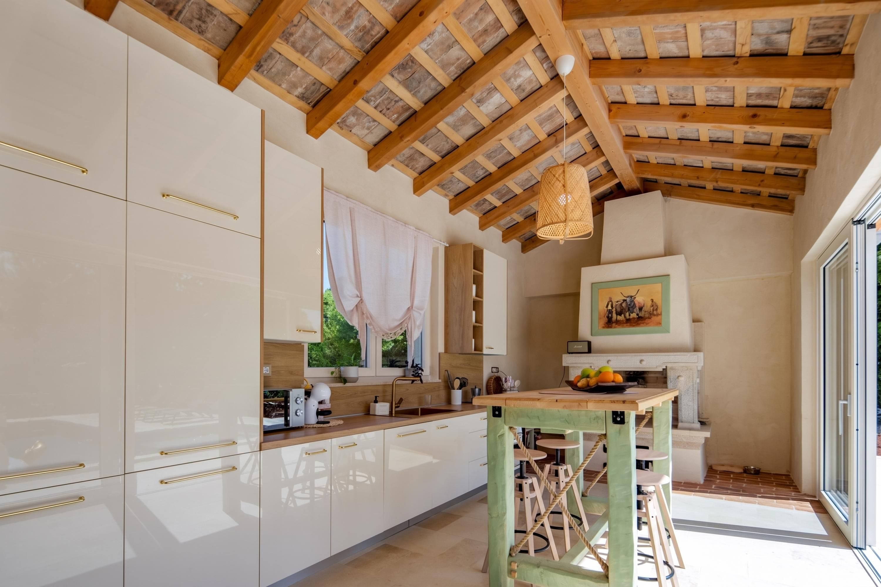 Cozinha moderna com armários brancos, teto de madeira e um espaço de refeições com banquetas.