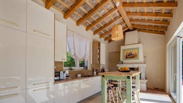 Cozinha moderna com armários brancos, teto de madeira e um espaço de refeições com banquetas.