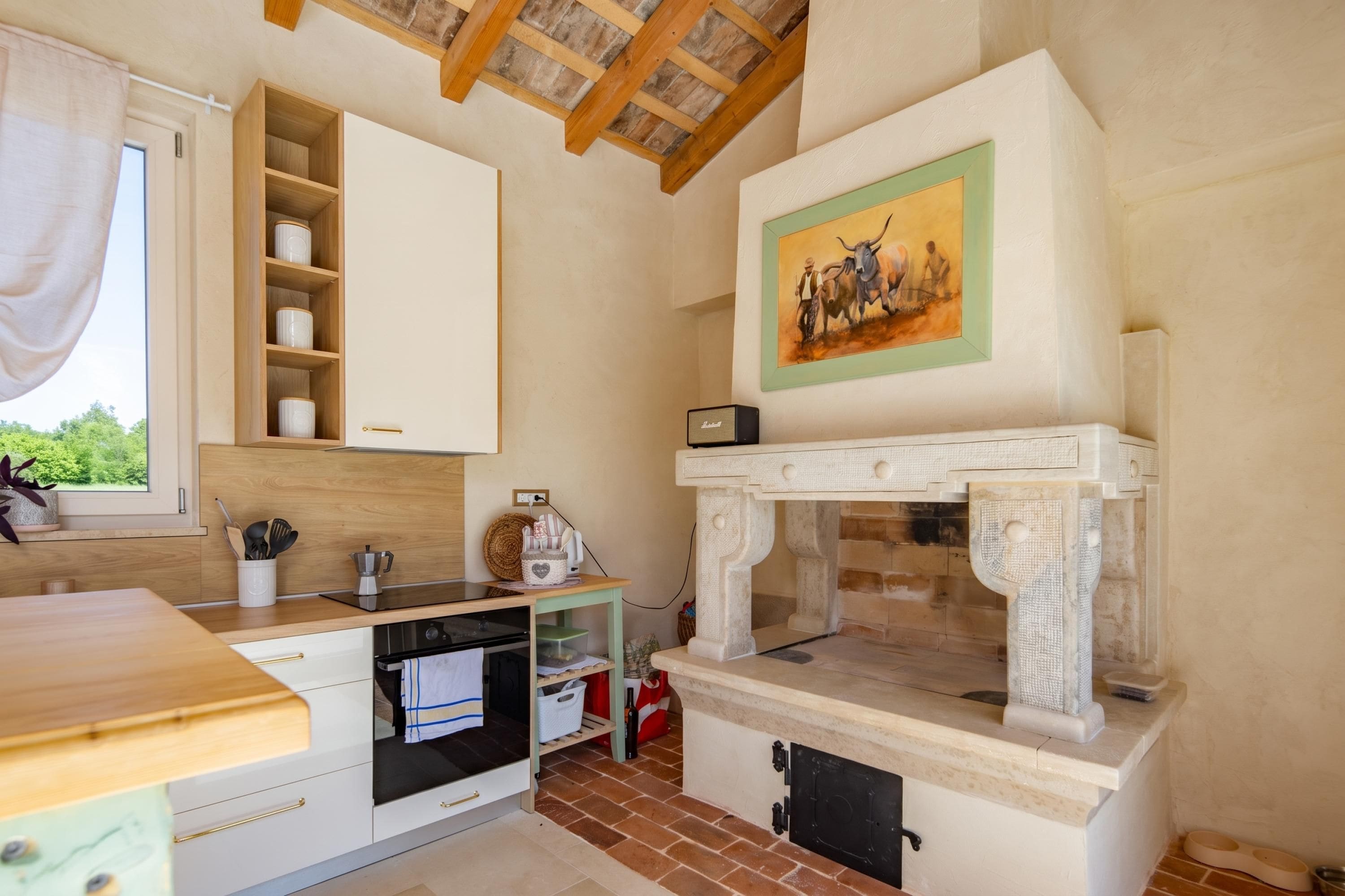 Una cocina con armarios de madera, microondas integrado y chimenea de piedra.