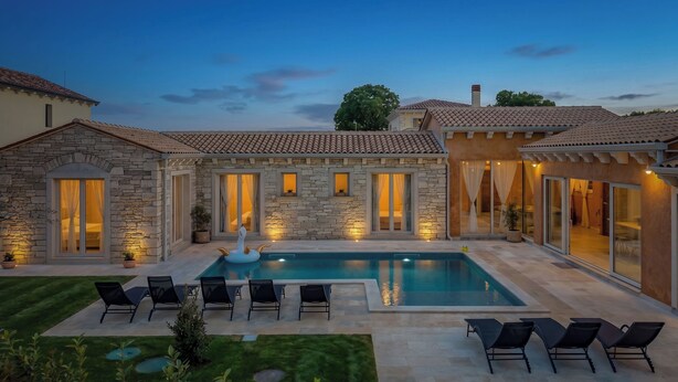 A pool with lounge chairs, stone walls, and a well-lit patio area. - Villa Stonica - Rustic Istrian Pool Retreat (Tinjan)