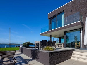 Ein modernes Gebäude mit Balkon, Außenbereich und Blick auf das Wasser.