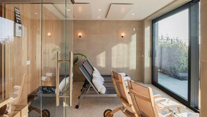 Un bagno moderno con pareti divisorie in vetro, un mobile bagno in legno, una poltrona massaggiante e una grande finestra.