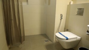 Un baño con ducha, inodoro y un cubo de basura.