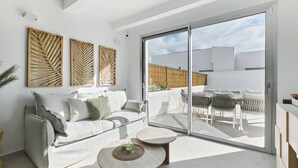 Ein modernes Wohnzimmer mit einer Couch, einem Couchtisch und einer Schiebetür zu einer Terrasse.