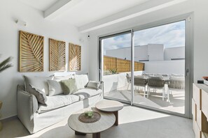 Ein modernes Wohnzimmer mit einer Couch, einem Couchtisch und einer Schiebetür zu einer Terrasse.