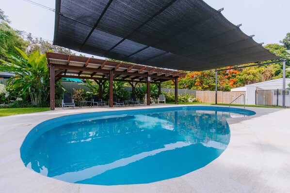 A swimming pool with a covered seating area and a pergola. - Kooyong Aprtments (Arcadia)
