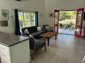 A modern living room with a sofa, a wooden table, and a kitchen area with cabinets. - Kooyong Aprtments (Arcadia)