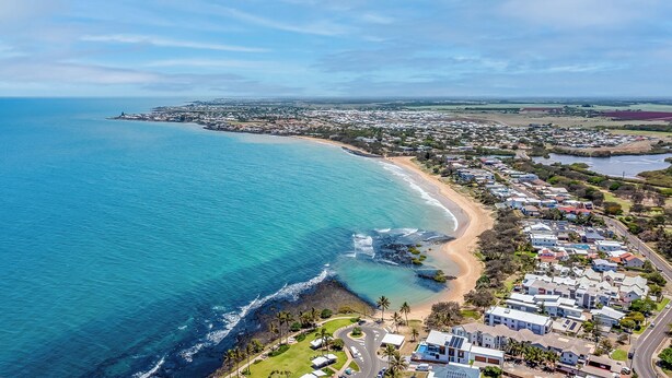 An aerial view of a coastal residential area with houses, a beach, and a clear blue ocean. - 2 Bedroom Unit with Beach & Golf at your doorstep! (Bargara)