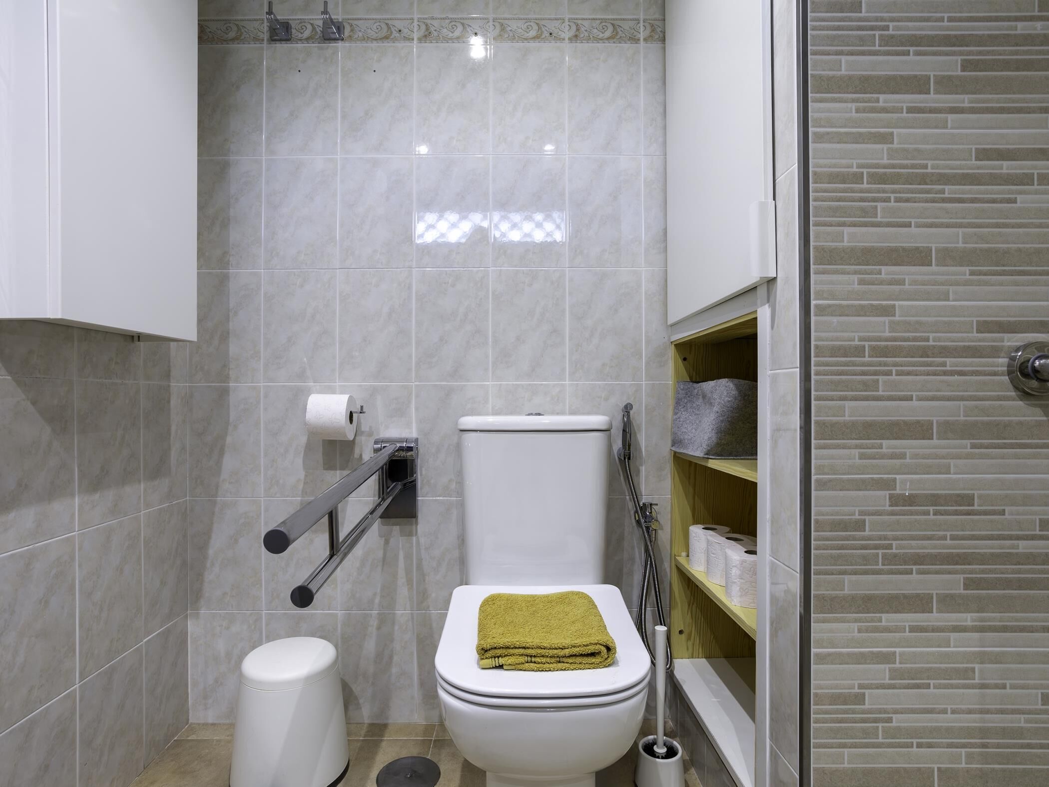 Een badkamer met een toilet, bidet en een plank met handdoeken.