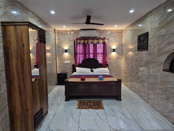 A bedroom with a bed, a ceiling fan, a wall-mounted air conditioner, and a mirror. - Eva Beach Hotel (Varkala)