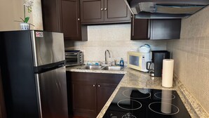 Una cucina con frigorifero in acciaio inossidabile, forno integrato, microonde, lavello e piano cottura.