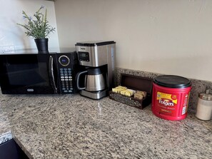 A kitchen with a microwave, coffee maker, and a Folgers coffee jar. - Unbeatable location, Multiple beds (San Diego)