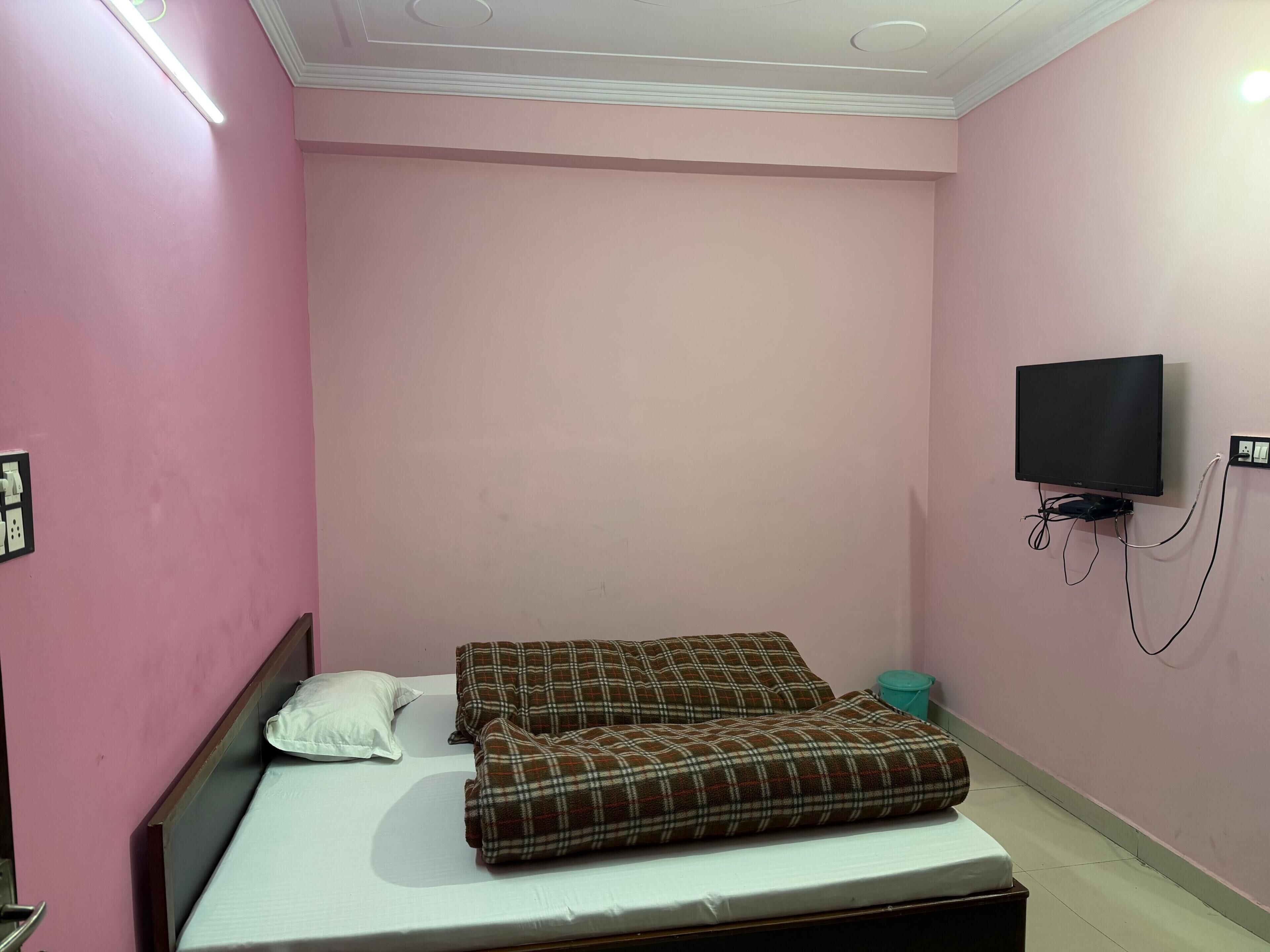 Ein Schlafzimmer mit einem Bett, einem Fernseher und einer Steckdose.