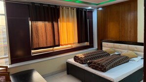 Un dormitorio con cama, ventana con cortinas, ventilador de techo y una mesa.