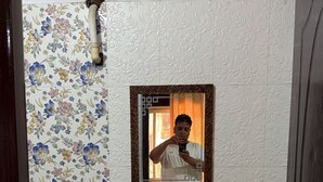 Un baño con pared de estampado floral, un lavabo blanco y un espejo con marco decorativo.