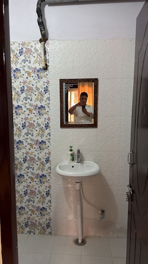 Ein Badezimmer mit blumengemusterten Wandfliesen, einem weißen Waschbecken und einem Spiegel mit Zierrahmen.