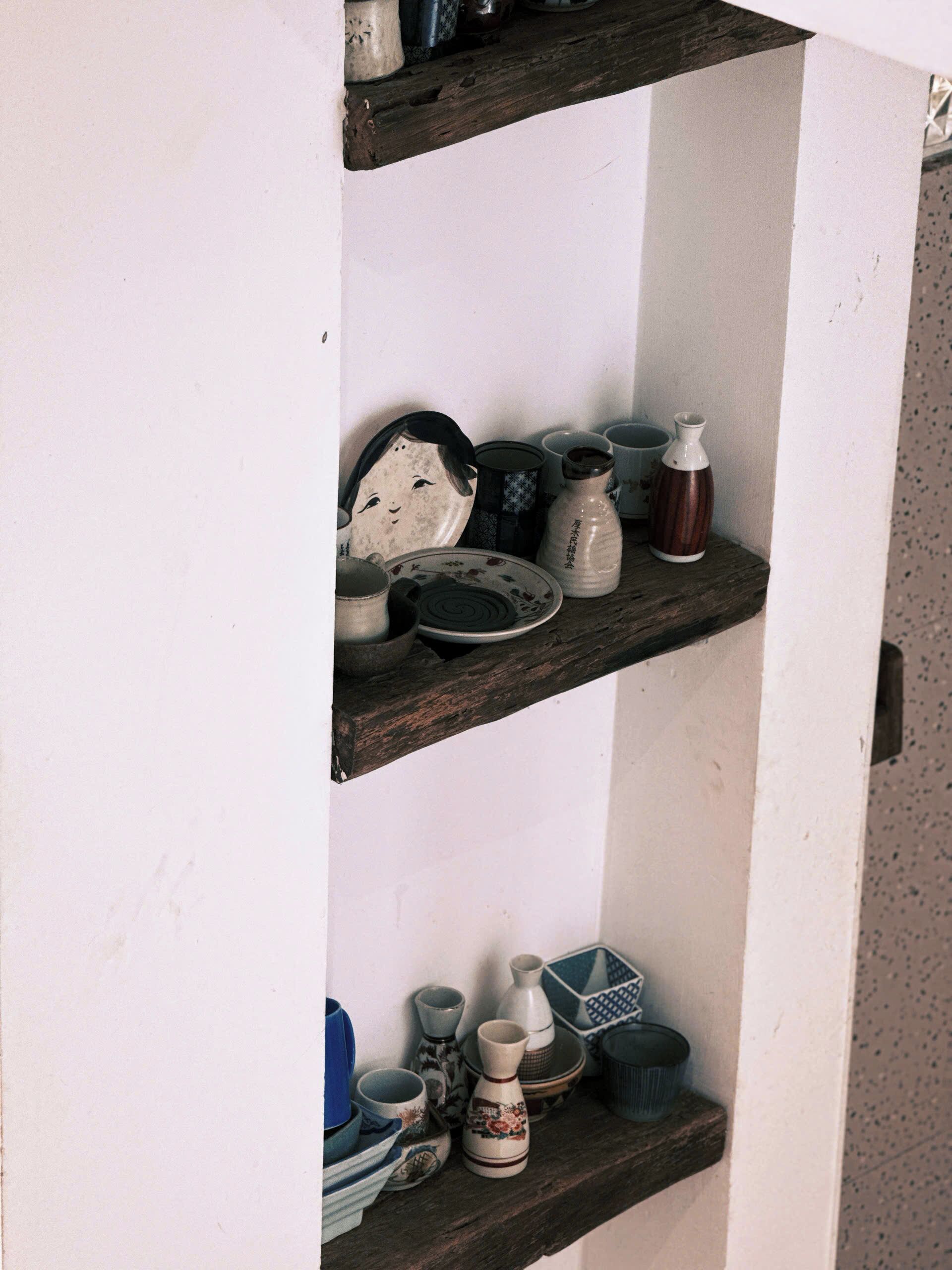 A shelf with various ceramic items including plates, bowls, and vases.
