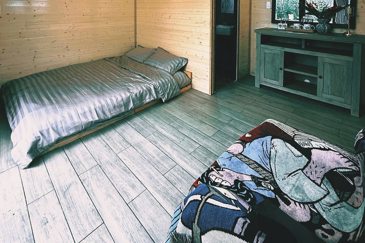 Un dormitorio con cama, televisor pequeño y ventana.