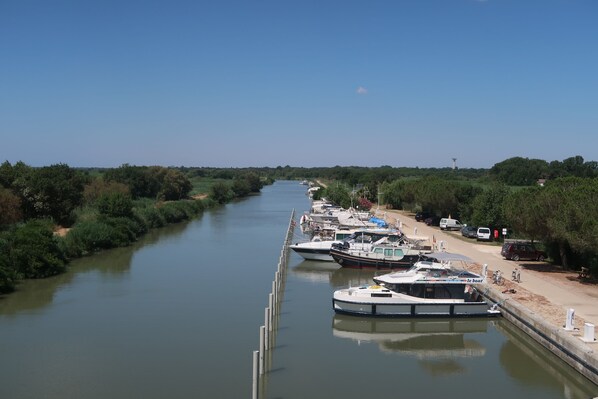 A canal with boats docked along the side, surrounded by greenery.