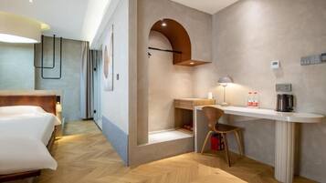 Una habitación de hotel moderna con cama, escritorio, silla y una pequeña zona de kitchenette.