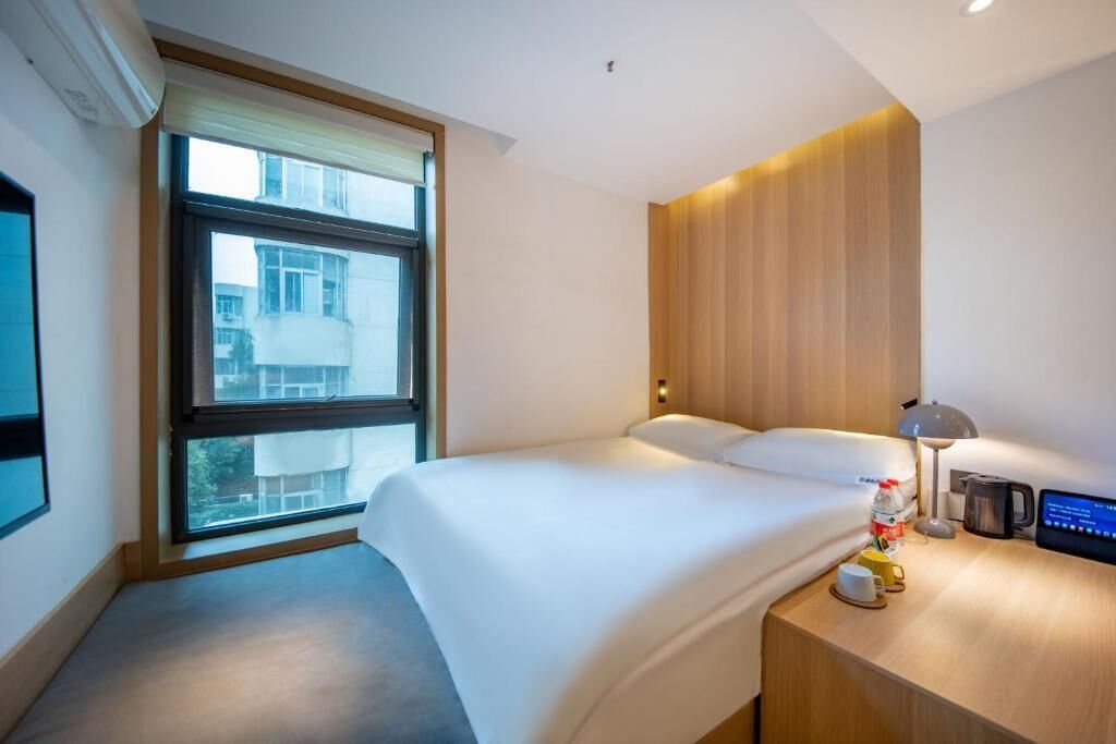 Ein Hotelzimmer mit einem Bett, einem Nachttisch mit Lampe, einer Kaffeemaschine und einem Fernseher.