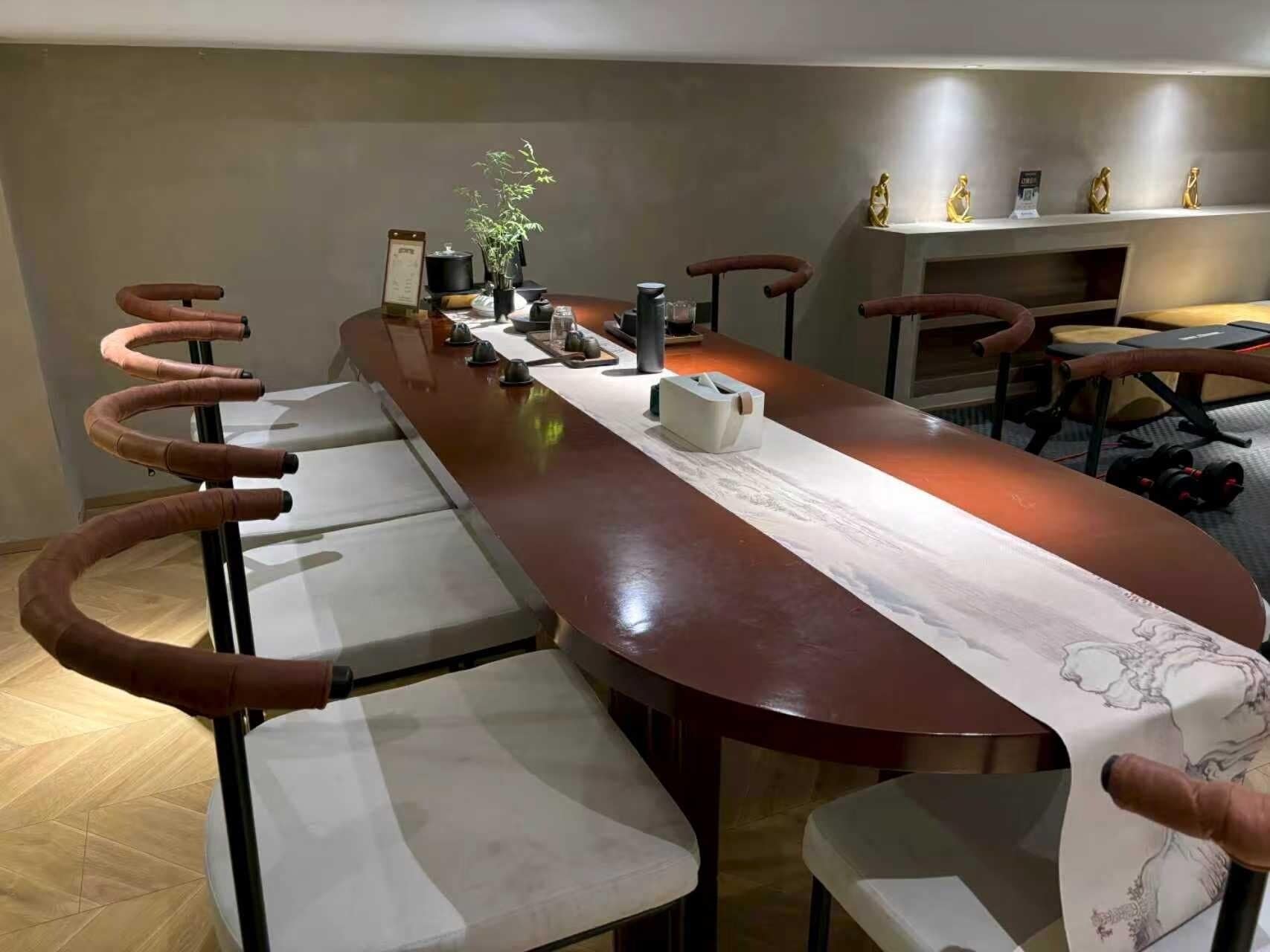 Een lange eettafel met stoelen, een vaas met een plant en een decoratieve tafelkleed.