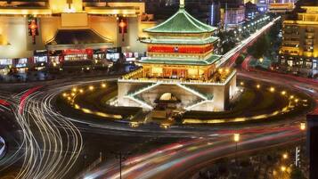 A traditional building with a green roof and multiple levels, surrounded by a roundabout with light trails indicating traffic.