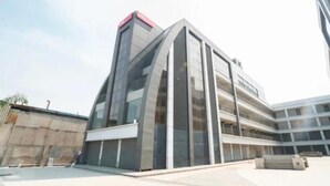 Ein modernes Gebäude mit einer geschwungenen Fassade, mehreren Etagen und einem flachen Dach.