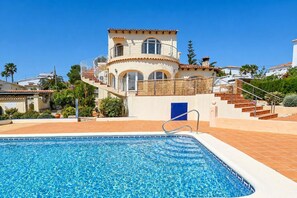 Ein zweistöckiges Haus mit Swimmingpool, Treppe und einer blauen Tür.
