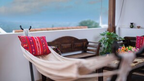 A hammock with red pillows, a wooden bench, and a table with a vase of flowers. - Casa de la Abuelita w/Private Pool & Volcano View (San Pedro Las Huertas)