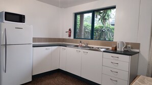 Eine kleine Küche mit Kühlschrank, Spüle und Fenster.