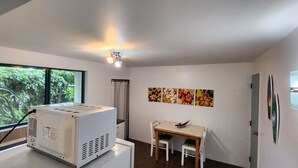 Ein Zimmer mit einer großen Klimaanlage, einem Tisch mit zwei Stühlen und einem Fenster mit Blick auf Grünflächen.