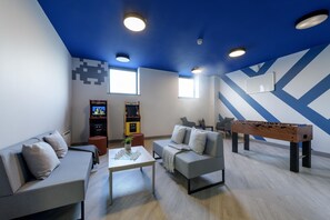 A modern living room with a foosball table, sofas, a coffee table, and a bookshelf. - Rosedale Court (Newcastle-upon-Tyne)