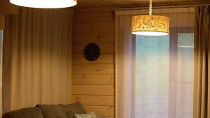 A cozy living room with a sofa, a coffee table, and two hanging lamps. - MATRYOSHKA HOUSE (Yoichigun)