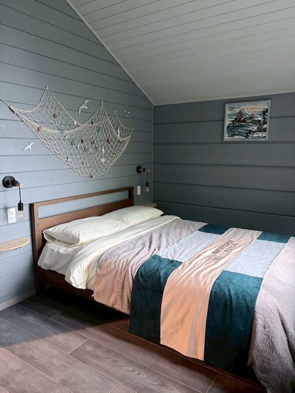 A bedroom with a bed, a hanging net decoration, a framed picture on the wall, and a wooden headboard.