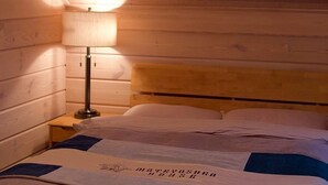 A wooden-paneled room with a bed, a nightstand, and a lamp. - MATRYOSHKA HOUSE (Yoichigun)