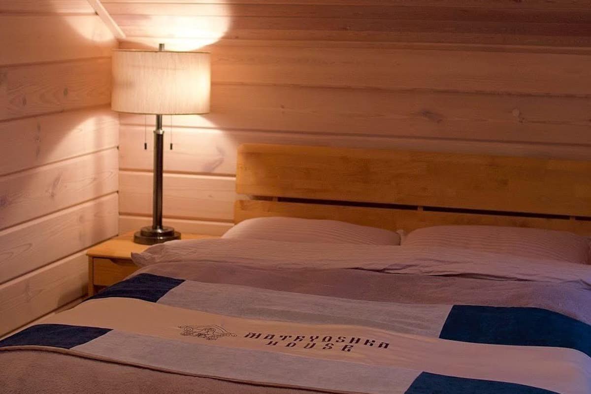Una habitación con paneles de madera, una cama, una mesita de noche y una lámpara.