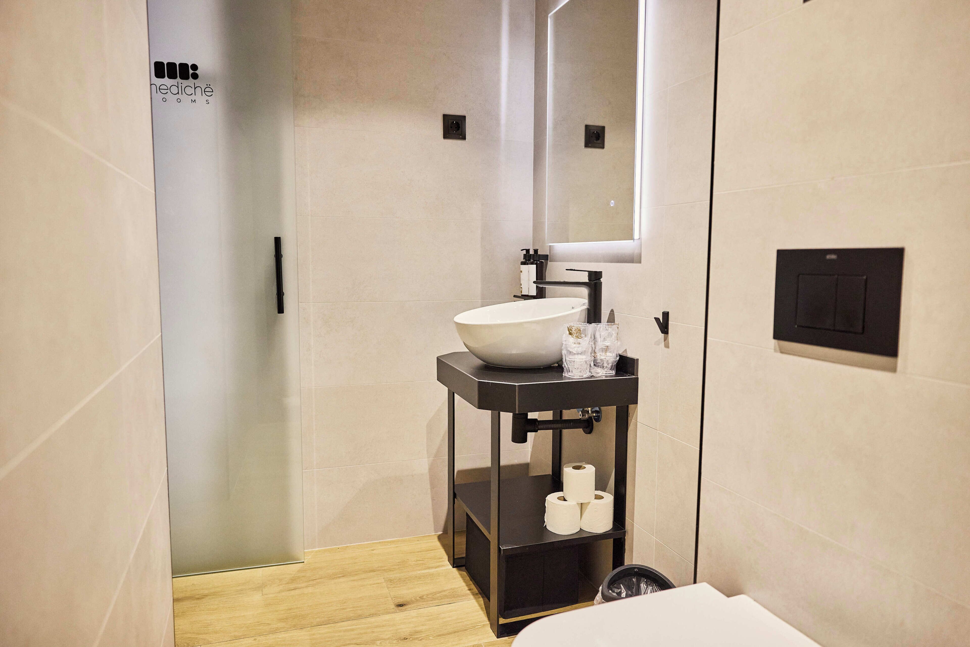 Un baño moderno con un espejo grande, un lavabo blanco y un mueble de tocador negro.