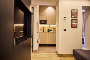 A modern kitchen with wooden cabinets, a microwave, and a coffee maker. - Medichë Rooms General Ricardos (Madrid)