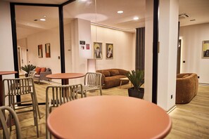 A modern interior with a wooden floor, a brown sofa, a round table, and a white chair. - Medichë Rooms General Ricardos (Madrid)