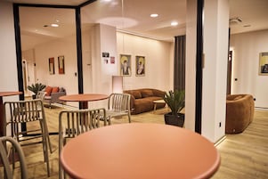 A modern interior with a wooden floor, a brown sofa, a round table, and a white chair.