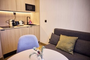A compact living space with a kitchenette, a sofa, and a dining area. - Medichë Rooms General Ricardos (Madrid)