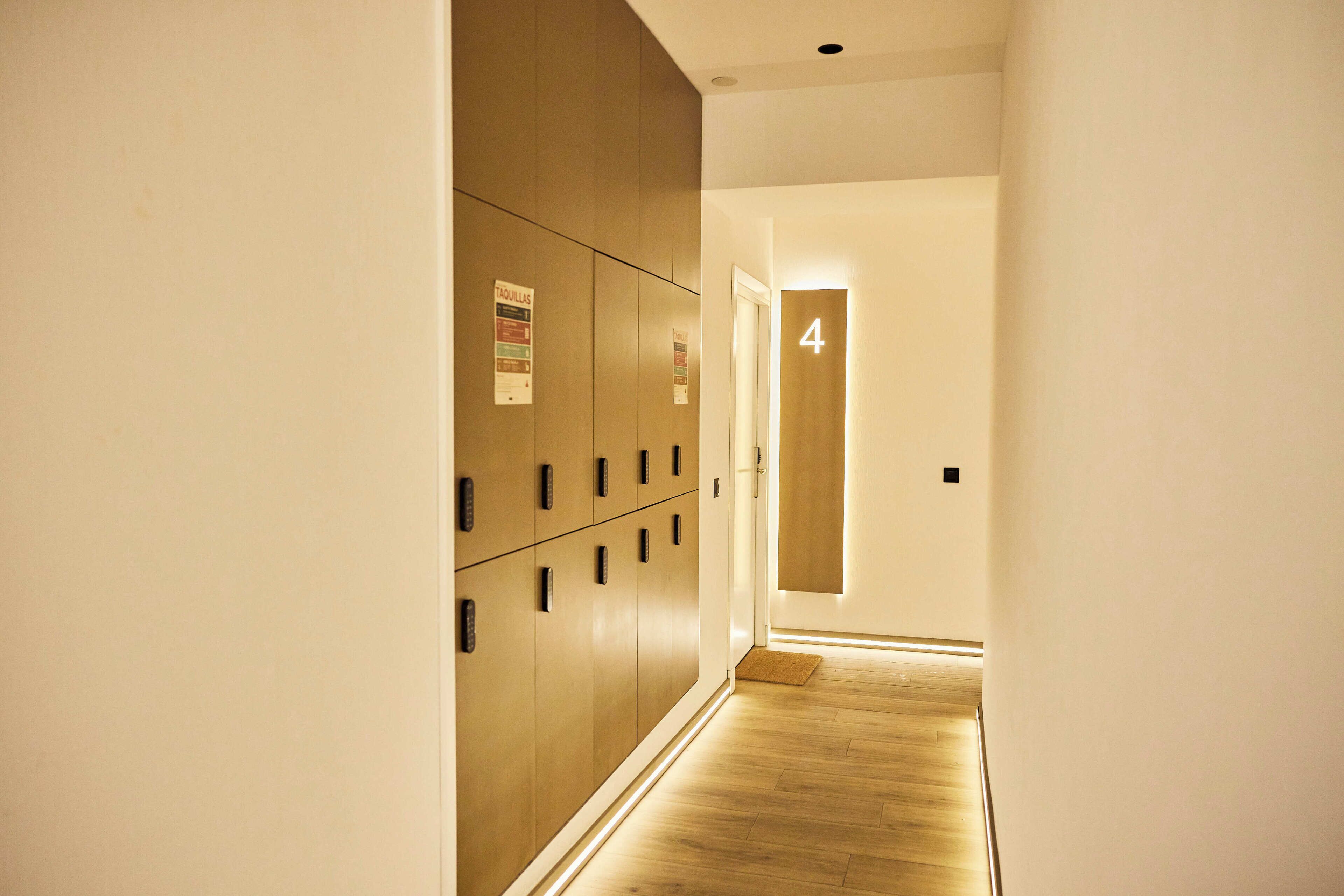 Pasillo de hotel con taquillas, una puerta numerada con el número 4 y piso de madera.