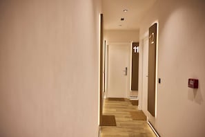 A hotel hallway with doors numbered 11 and 12, wooden flooring, and a fire alarm on the wall. - Medichë Rooms General Ricardos (Madrid)
